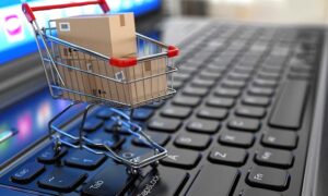 E-commerce. Shopping cart with cardboard boxes on laptop. 3d